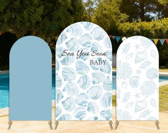 May include: Three arched backdrop covers featuring a solid light blue panel, a central panel with a blue seashell pattern and the text Sea You Soon BABY, and a right panel with a blue and white pattern of various seashells and coral reefs.