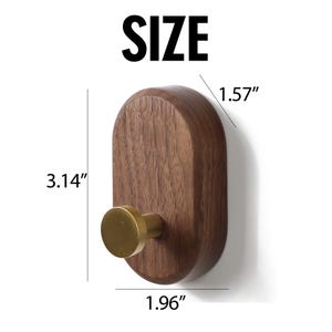 May include: A wooden wall hook with a brass knob. The hook is 8 cm tall, 5 cm wide, and the knob extends 4 cm. The word "SIZE" is printed in large, bold, black letters above the hook.