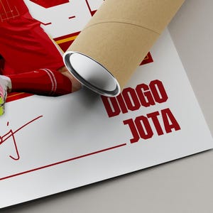 Pode incluir: Um p&ocirc;ster com um jogador de futebol em uniforme vermelho, com o nome "DIOGO JOTA" em letras vermelhas em negrito. A assinatura do jogador e o n&uacute;mero 20 tamb&eacute;m s&atilde;o vis&iacute;veis. Um tubo de p&ocirc;ster enrolado est&aacute; no canto superior direito.
