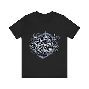 May include: Black t-shirt featuring a detailed, stylized design with the text "Built of Starlight & Spite." The design includes a star, crescent moon, and swirling elements in shades of gray and white.