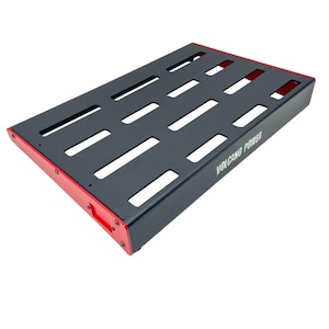 May include: A black rectangular pedalboard with red trim. The pedalboard has multiple rectangular cutouts and the words "VOLCANO POWER" printed on the side. The pedalboard is designed to hold guitar effects pedals.