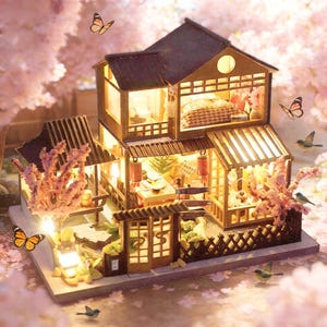 Op de afbeelding: Een miniatuur houten huis in Japanse stijl met binnenverlichting, met een gedetailleerd ontwerp met meerdere kamers, een kleine tuin en een traditionele poort. De scène is versierd met roze kersenbloesemtakken, vlinders en kleine vogels.