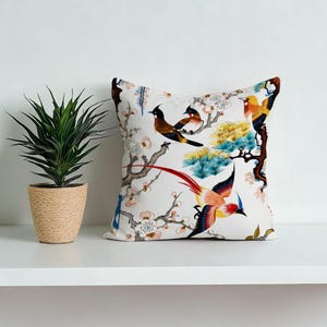 May include: A white ceramic mug with a black handle and the text "But First, Coffee" in a bold, black font. The mug is set against a blurred background, suggesting a cosy setting.