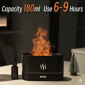 May include: Black essential oil diffuser with a flame effect. The diffuser has a capacity of 180ml and can be used for 6-9 hours. A small bottle of essential oil is next to the diffuser. The diffuser has a flame design.