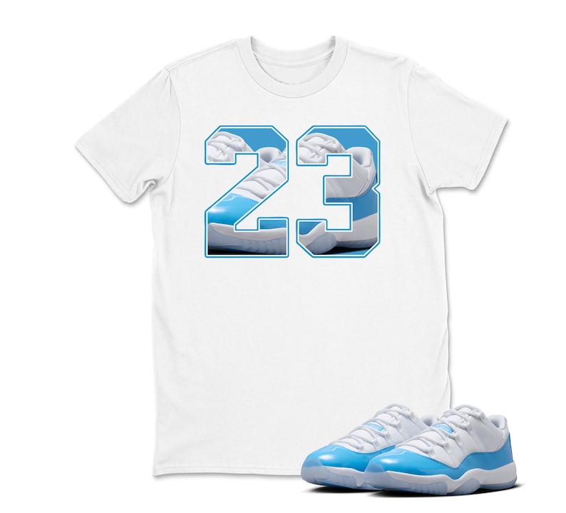 May include: White t-shirt with a blue outline of the number 23, filled with a photo of a blue and white sneaker. A pair of matching blue and white sneakers are in front of the shirt.