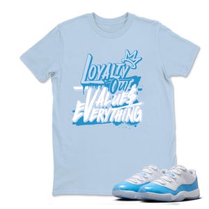 Peut inclure: Un t-shirt bleu clair avec le texte "Loyalty Over Values Everything" en blanc et bleu. Une paire de baskets bleu clair et blanches est devant le t-shirt.