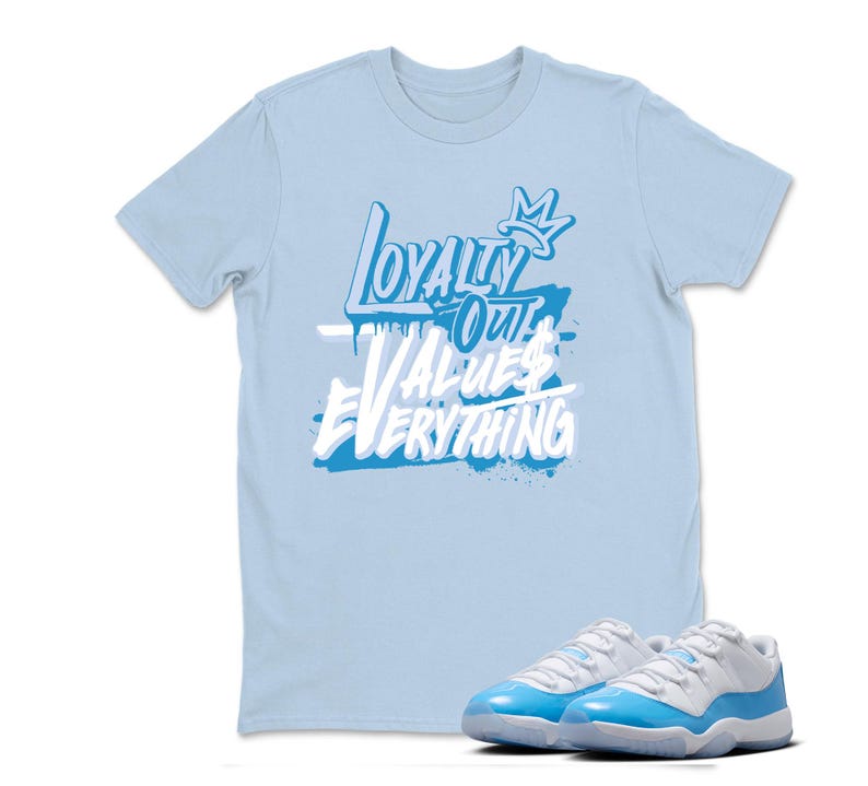 Peut inclure: Un t-shirt bleu clair avec le texte "Loyalty Over Values Everything" en blanc et bleu. Une paire de baskets bleu clair et blanches est devant le t-shirt.