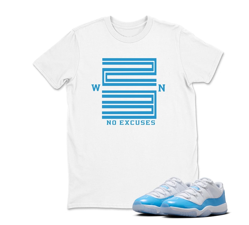 May include: White t-shirt featuring a blue graphic with the text "W 23 N NO EXCUSES." A pair of white and light blue trainers are in the foreground. The t-shirt is a casual style.