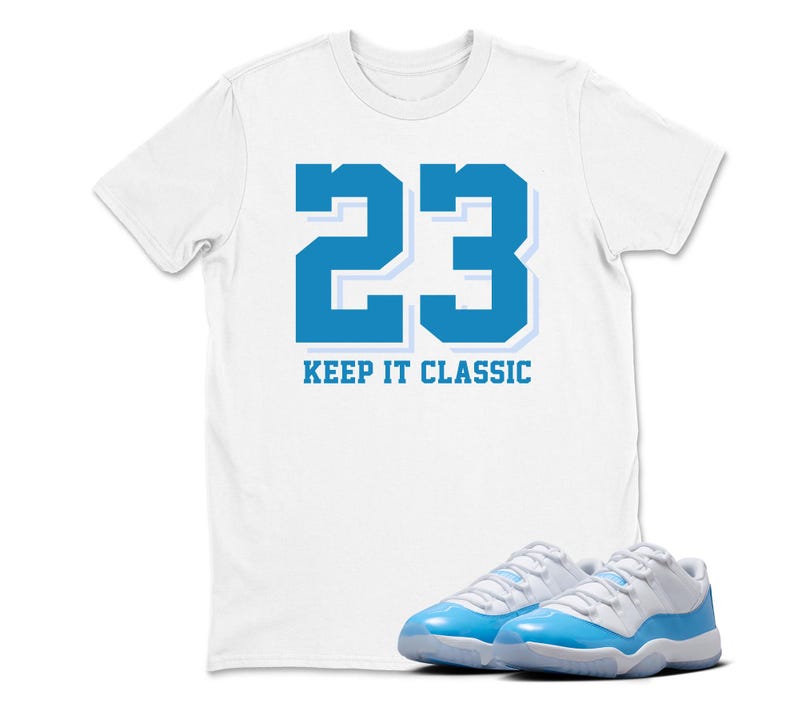Puede incluir: Camiseta blanca con el n&uacute;mero 23 en azul y el texto "KEEP IT CLASSIC". Un par de zapatillas azules y blancas est&aacute;n en la parte inferior de la imagen.