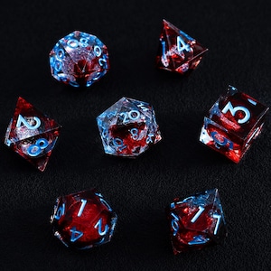 May include: A set of seven polyhedral dice made of translucent resin, featuring a deep red core with swirling silver glitter inclusions and bright light blue numbers. The collection includes various geometric shapes used for tabletop gaming.