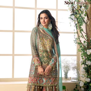 Op de afbeelding: Een ingewikkeld ontworpen, lange mouwen ensemble in tinten van teal, rood en goud. De outfit heeft gedetailleerde patronen, een bijpassende sjaal en kralen accenten. Het ensemble is een traditionele stijl, geschikt voor speciale gelegenheden.