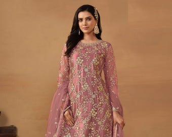Op de afbeelding: Een stofroze Sharara-pak met ingewikkelde bloemenborduurwerk. De set bevat een tuniek met lange mouwen, een broek met wijde pijpen en een bijpassende doorschijnende dupatta. De outfit is versierd met goudkleurige accenten en de tekst "Siya Couture".