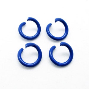 May include: Four blue metal jump rings, each with a gap in the circle, are arranged in a square pattern on a white background.