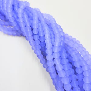 May include: A strand of light blue frosted glass beads. The beads are round and have a matte finish.