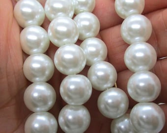 May include: A strand of white faux pearl beads. The pearls are round and smooth, and they are strung on a clear thread.