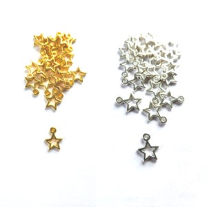 May include: A selection of gold and silver star-shaped charms, ideal for jewellery making. Each charm has a small loop and a hollow design. The image displays a variety of charms, suitable for crafting projects.