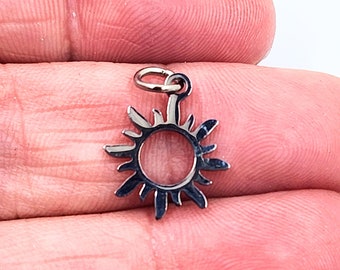 May include: A silver sun charm pendant with a circular center and a detailed sunburst design.