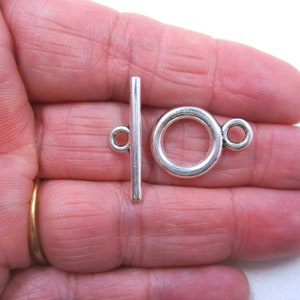 May include: Silver toggle clasp with a round ring and a straight bar. The clasp is designed for jewellery making and is approximately 2.5 cm in length.