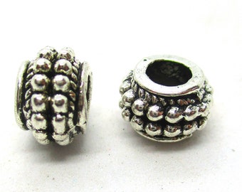 May include: Two silver metal beads with a textured design. The beads have a round shape and a hole in the center.