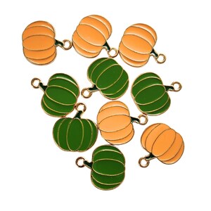 May include: A group of ten metal pumpkin charms in orange and green. The charms have a gold finish and are perfect for adding a touch of autumn to your crafts.