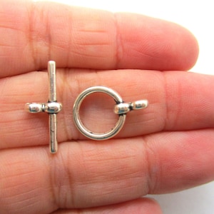 May include: Silver-toned toggle clasp with a round ring and a straight bar. The clasp is designed for jewellery making and is approximately 2.5 cm in length.