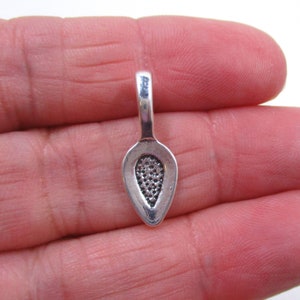 May include: Silver-toned metal pendant with a teardrop shape and a textured design. The pendant has a loop at the top for attaching to a chain or cord.