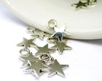 May include: A group of silver star-shaped charms with jump rings. The charms are scattered on a white surface.