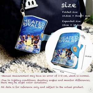 May include: A blue book-shaped accessory with the text "HEATED RIVALRY" and a hockey scene. Folded size is 10.5cm x 8cm x 5cm, expanding to 18cm x 10.5cm. It has a button closure and a small bunny charm.