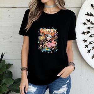 Puede incluir: Camiseta negra con un gráfico colorido de la serie animada "Gravity Falls". El diseño incluye el título del programa y varios personajes. La camiseta está hecha de un material suave.