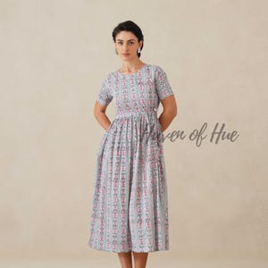 May include: A light blue dress with a vertical striped pattern of pink floral accents. The dress has short sleeves and a cinched waist. The text "Raven of Hue" is visible on the right side of the image.