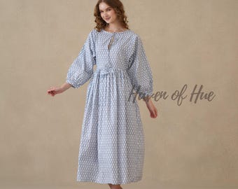 May include: A light blue and white midi dress featuring a repeating diamond pattern, long puff sleeves with elastic cuffs, a round neckline with a tie closure, and a gathered waist. The text Haven of Hue is visible on the right side.