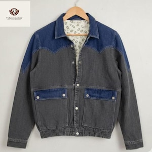 Puede incluir: Chaqueta vaquera bicolor gris y azul. Presenta cuello camisero, cierre de botones y dos bolsillos delanteros. Los hombros y el cuello son de color azul oscuro, mientras que el cuerpo es gris. El forro tiene un estampado.