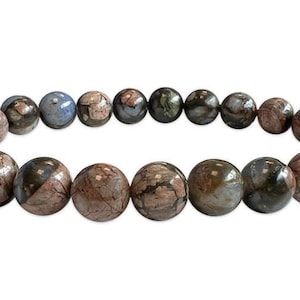 Könnte beinhalten: Ein Armband mit runden, polierten Perlen in Braun-, Grau- und Blautönen. Die Perlen haben ein marmoriertes Aussehen, das eine natürliche Ästhetik erzeugt. Das Armband ist auf einem elastischen Band aufgefädelt. Jede Perle misst ca. 1,5 cm im Durchmesser.