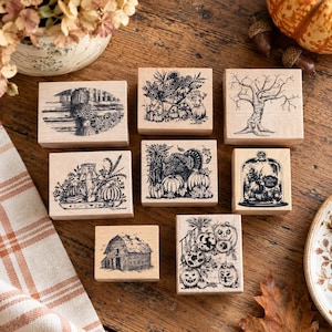 May include: A collection of eight rectangular wooden rubber stamps featuring black ink illustrations of autumn themes including a barn, a bare tree, a turkey, pumpkins, and a glass cloche with the text The Pumpkin Patch.