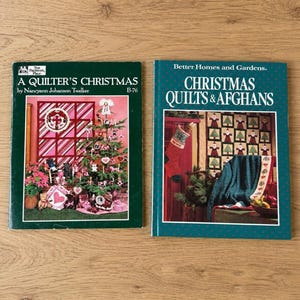 May include: Two softcover craft books with dark green covers. The left book is titled A Quilter's Christmas by Nancyann Johanson Twelker, featuring a decorated Christmas tree. The right book is titled Christmas Quilts & Afghans, showing a stocking.