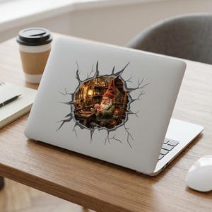 May include: Laptop sticker featuring a whimsical illustration of a gnome in a workshop. The gnome, wearing a red hat and green coat, is surrounded by tools and a warm light. The sticker appears to be breaking through the laptop's surface.