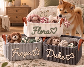 May include: Three rectangular storage baskets made of ribbed fabric with brown leather-like handles. The white basket features the name Flora and a heart, the grey basket says Freya with a star, and the dark grey basket says Duke with a bone.