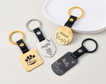 以下が含まれることがあります： 黒い革ストラップと金属製のタグが付いた4つのパーソナライズされたキーホルダー。 金色のタグには足跡と「Oliver」という名前があります。 別の金色のタグには、「Forest」という名前と森のデザインがあります。 銀色のタグには「Muffin」という名前と花の模様があります。 黒いタグには「Molly」という名前と花の模様があります。