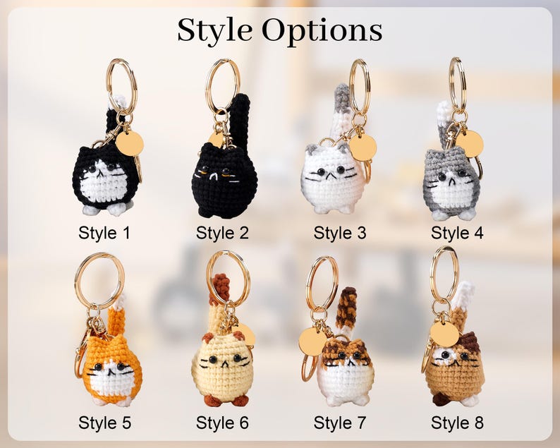 May include: A collection of eight crochet cat keychains, each with a gold-colored keyring and a small, round tag. The cats vary in color and pattern, including black, white, gray, orange, and brown. The text "Style Options" is at the top, with style numbers below each cat.