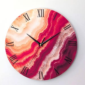 May include: A round wall clock featuring a vibrant agate-inspired pattern with swirling gradients of deep magenta, bright red, and soft peach. The clock face displays black Roman numerals and thin black hour, minute, and second hands.