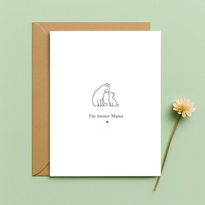 May include: A white greeting card with a line drawing of two cats, one larger and one smaller, with the German text "Für immer Mama" and a small red heart. The card is inside a brown envelope, with a dried flower on a stem.