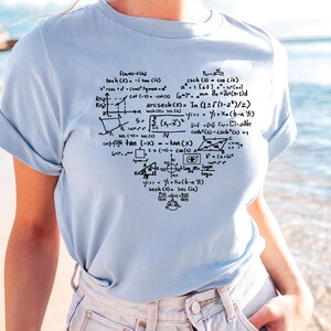 May include: Light blue t-shirt featuring a heart-shaped design filled with mathematical equations and formulas in black ink. The shirt is made of a soft material and has short sleeves.