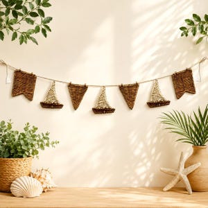 May include: A decorative garland featuring alternating woven brown wicker pennant flags and light-colored wicker sailboat shapes suspended on a thin twine string. The nautical-themed hanging ornament consists of seven distinct pieces arranged horizontally.