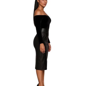 Puede incluir: Un top negro con hombros descubiertos y mangas largas con una falda l&aacute;piz negra. El atuendo se combina con tacones altos negros. El conjunto es un look monocrom&aacute;tico elegante.