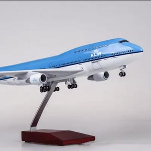 Op de afbeelding: Een blauw en wit KLM Boeing 747 modelvliegtuig. Het model is gemonteerd op een standaard met een donkere houten basis. Het vliegtuig heeft het KLM-logo en details.