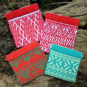 May include: Four square pouches featuring intricate geometric patterns. Two pouches display a red and white design, one features a red base with green patterns, and one has a teal base with light green patterns. Each pouch has a solid colored top band.