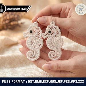 May include: A pair of white seahorse-shaped earrings with intricate lace-like detailing. Each earring features a black bead eye and a silver hook. The image also includes the text "EMBROIDERY FILES".