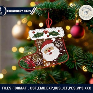 May include: A Christmas stocking ornament with a Santa Claus face and snowflake design, hanging on a Christmas tree. The ornament is red, white, and green, with the text "EMBROIDERY FILES" and "Pro Threads Co" visible.