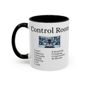 Könnte beinhalten: Weißer Keramikbecher mit schwarzem Innenraum und Griff. Der Becher zeigt die Worte "Control Room" und ein Bild einer Person vor mehreren Monitoren. Text auf dem Becher enthält Akronyme und Phrasen.