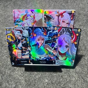 Op de afbeelding: Een verzameling kleurrijke ruilkaarten met illustraties in anime-stijl. De kaarten tonen het personage Yamato in verschillende actieposes en levendige achtergronden. Elke kaart heeft een waarde van 5000.